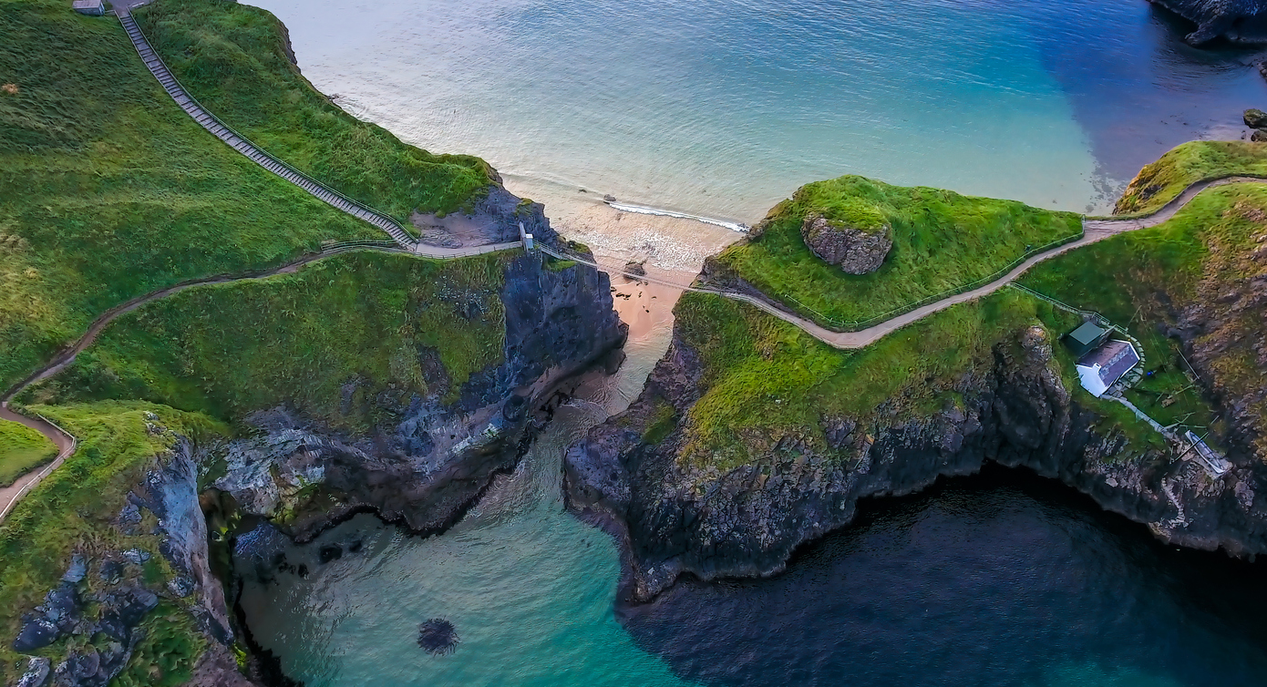 The rope bridge connecting the two cliffs in Northern Ireland it is called the Carrick-a-Rede Rope Bridge taken in an aerial shot