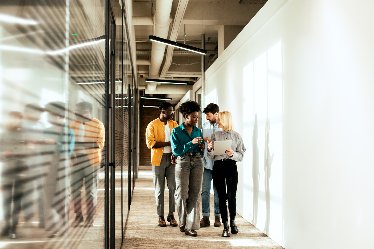 A group of coworkers having a casual chat in their shared office hallway