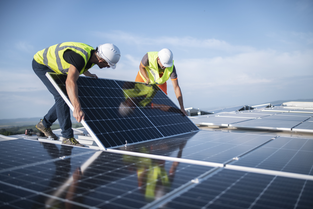 An image of two engineers installing solar panels on roof.